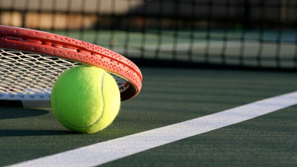 Close shot of a tennis racket and tennis ball.