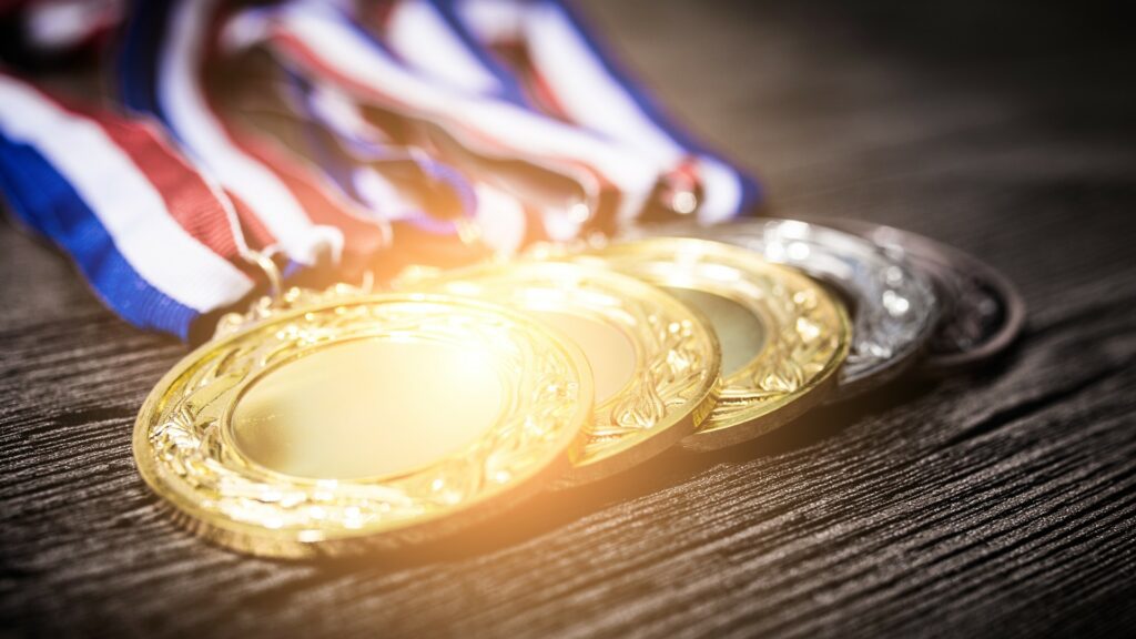 Close shot of three gold and two silver medals.